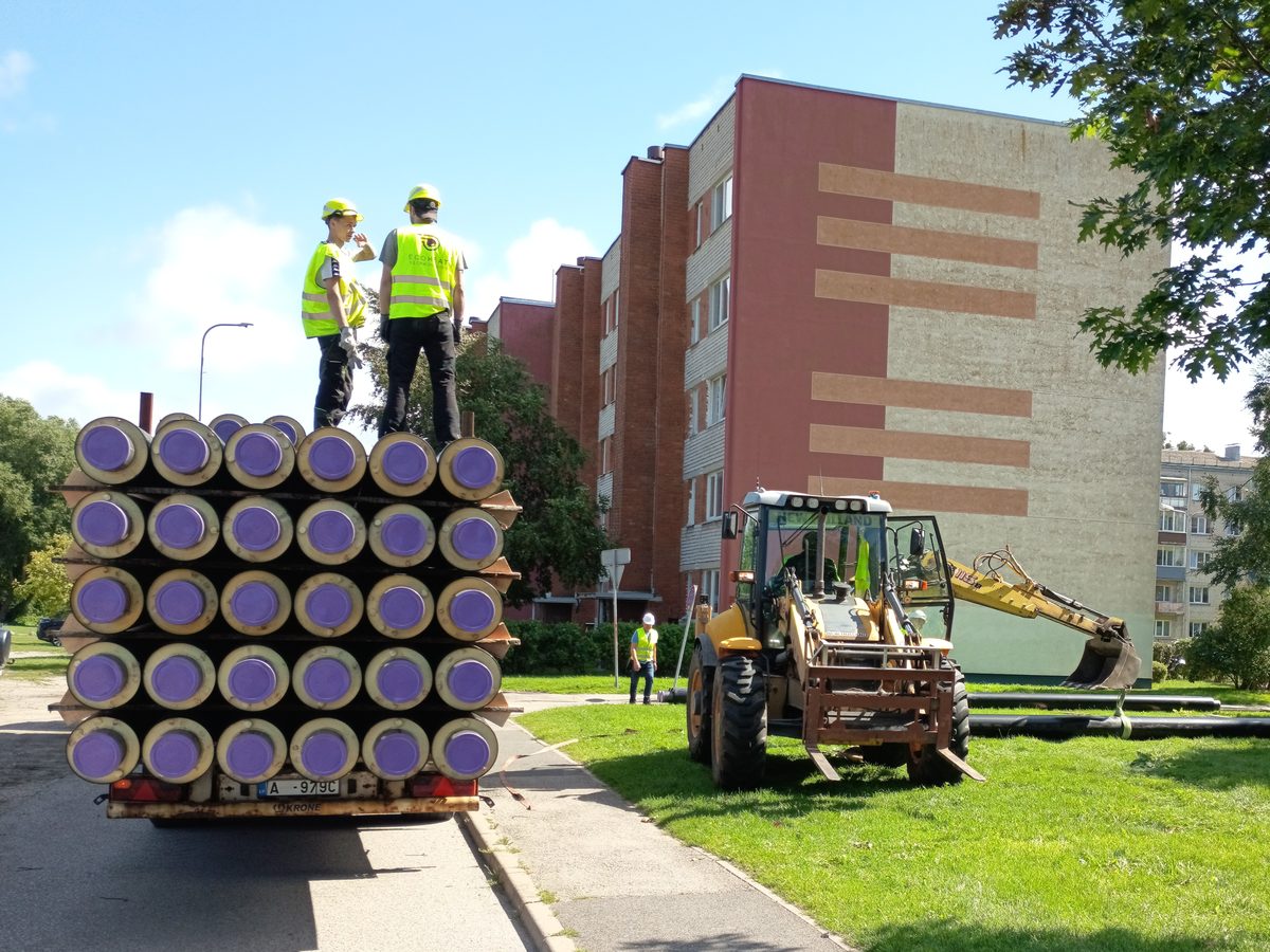 Strādnieki pie cauruļu kravas, kas nostiprināta uz platformas